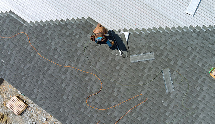 asphalt shingle roof being installed by a worker